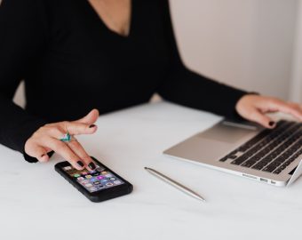 crop woman using smartphone and laptop during work in office